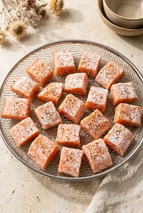 Seasoned salmon cubes arranged in a single layer in an air fryer basket before cooking.