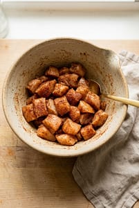 Seasoned diced chicken breast coated in spices in a mixing bowl under soft natural light.